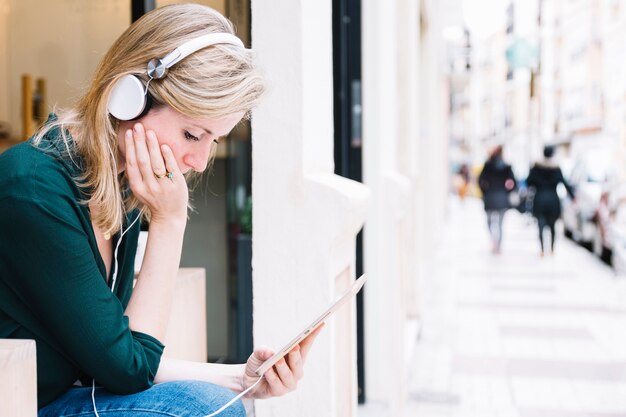 Femme avec tablette assis sur la rue