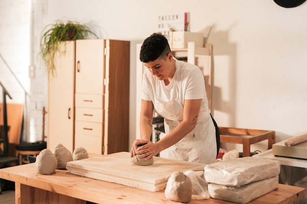 Femme en tablier à pétrir l&#39;argile dans l&#39;atelier