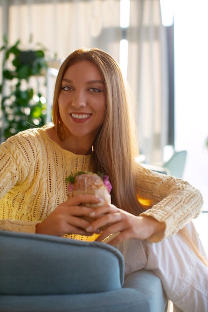 Une femme de taille moyenne avec un sandwich enveloppé en papier.