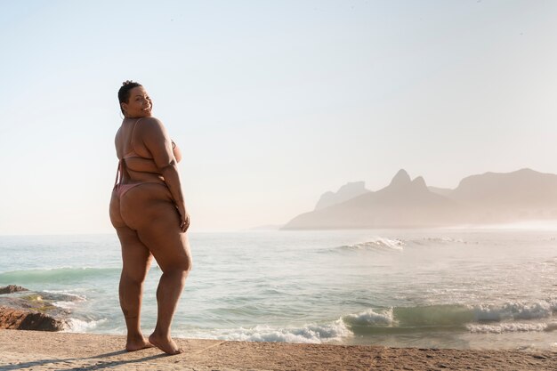 Une femme en taille plus posant au bord de la mer