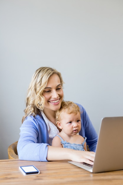 Femme taper sur un ordinateur portable avec un bébé sur les jambes