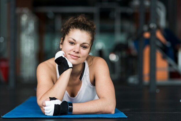 Femme sur tapis de yoga en regardant la caméra