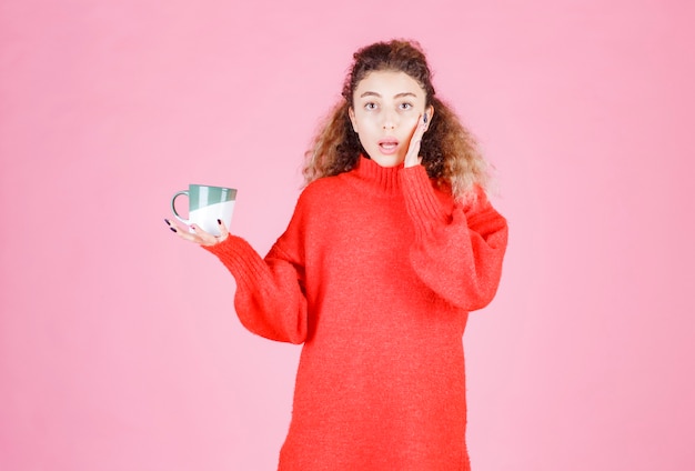 femme avec une tasse de café a l'air surprise.