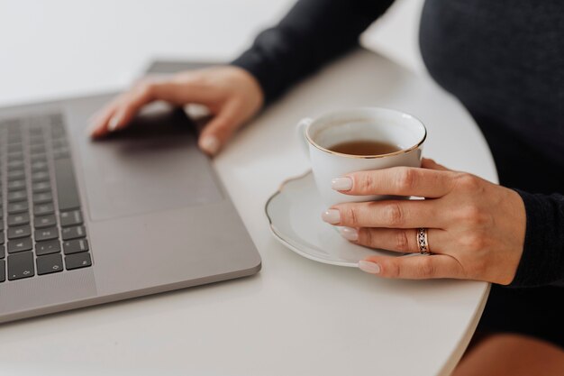 Femme avec une tasse de thé et un ordinateur portable