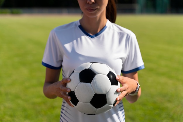 Femme tenant un ballon de football sur le terrain