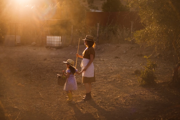 Femme tenant un bâton debout avec sa fille dans le champ