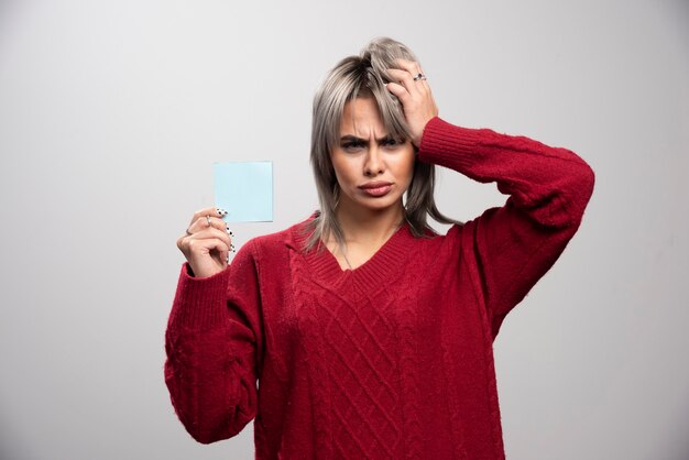 Femme tenant un bloc-notes et pensant au travail.