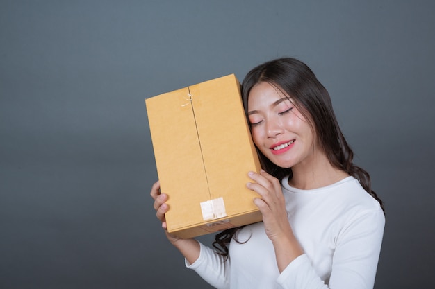 Femme tenant une boîte postale brune Fait des gestes avec la langue des signes.