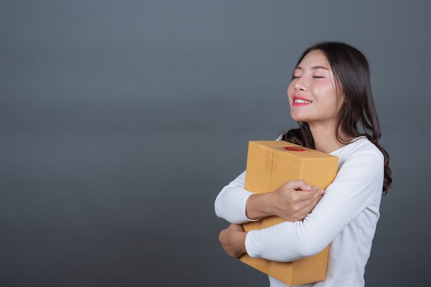 Femme tenant une boîte postale brune Fait des gestes avec la langue des signes.