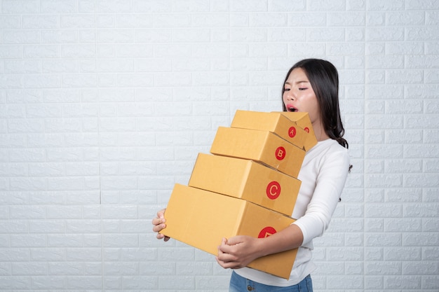 Femme tenant une boîte postale brune Fait des gestes avec la langue des signes.