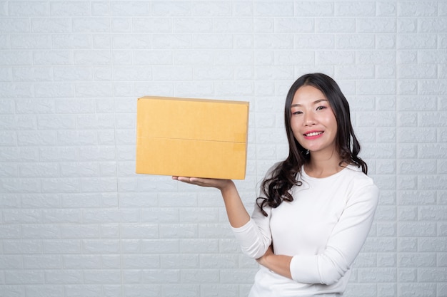 Femme tenant une boîte postale brune Fait des gestes avec la langue des signes.