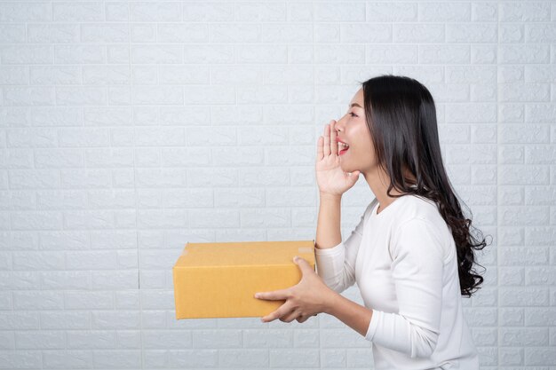 Femme tenant une boîte postale brune Fait des gestes avec la langue des signes.