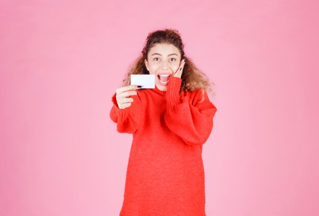 femme tenant une carte de visite a l'air très heureuse et surprise.