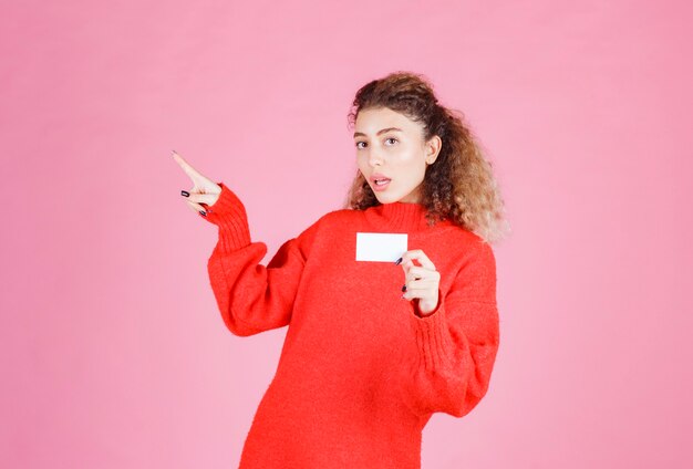 femme tenant une carte de visite et présentant son collègue.