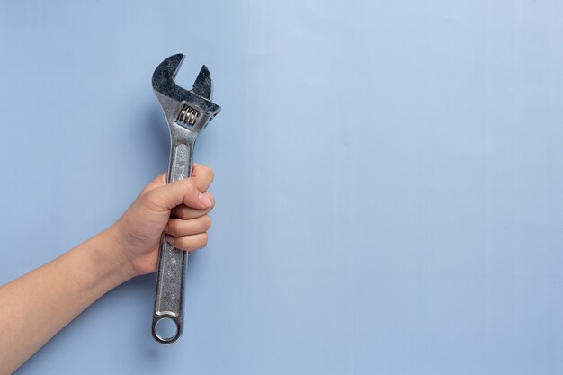 Femme tenant une clé en métal, concept de fond de la fête du travail