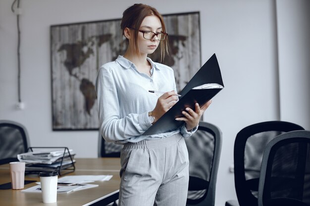 Femme tenant un dossier Fille signe les documents. Beauté à lunettes.