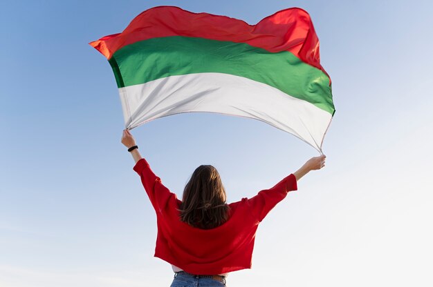 Femme tenant le drapeau bulgare contre le drapeau bleu