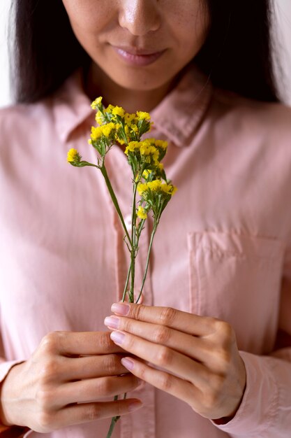 Femme tenant des fleurs jaunes se bouchent