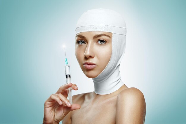 Femme tenant l'injection de botox avec tête bandée