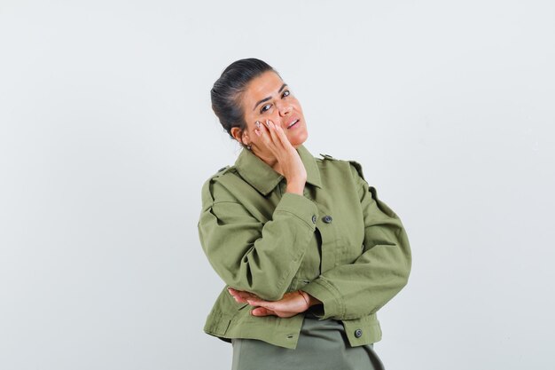 femme tenant la main sur la joue en veste, t-shirt et à la confiance