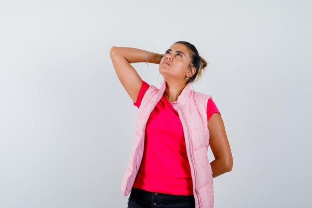 Femme tenant la main sur la tête en t-shirt, gilet et à la pensive