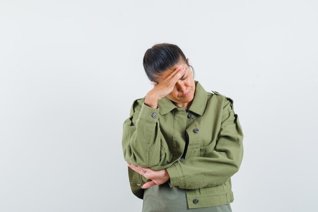 Femme tenant la main sur la tête en veste, t-shirt et à la tristesse