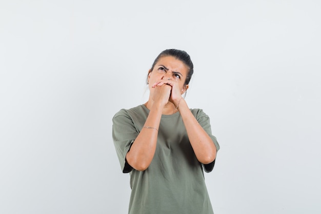 femme tenant les mains jointes en t-shirt et à hésitant