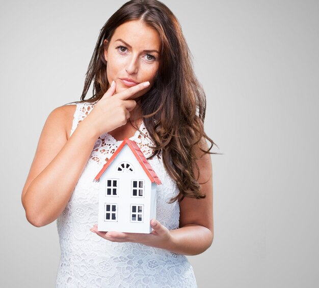 femme tenant une maison et penser à quelque chose