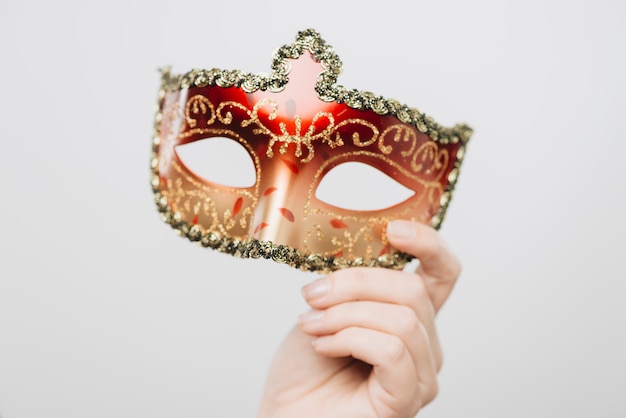 Femme tenant un masque de carnaval rouge à la main