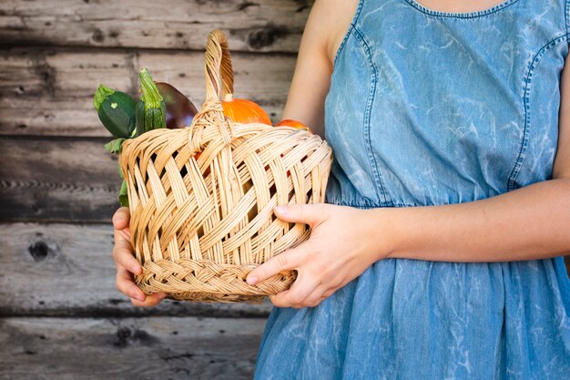 Femme tenant un panier de légumes près de sa poitrine