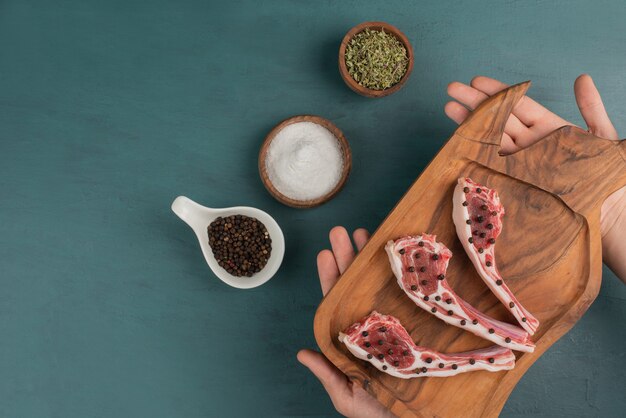 Femme tenant une planche de bois de morceaux de viande crue.