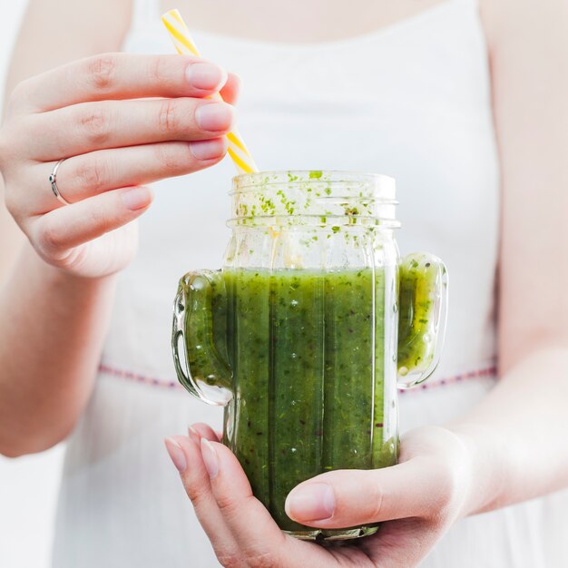 Femme tenant un pot avec un smoothie sain