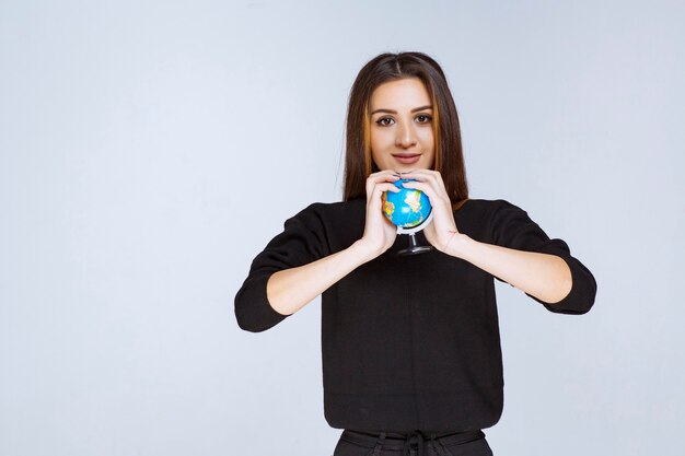 femme tenant et promouvant un mini globe.