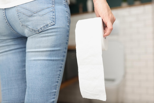 Une femme tenant un rouleau de papier toilette dans les mains est venue dans les toilettes
