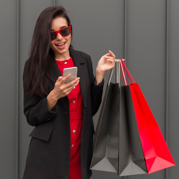 Femme tenant des sacs à provisions et regardant le téléphone