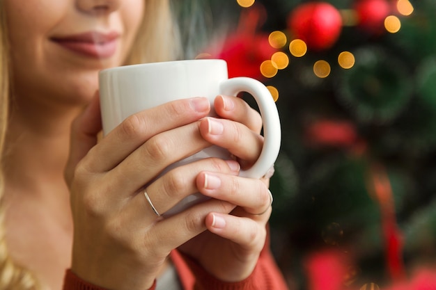 Femme tenant une tasse en face de son visage