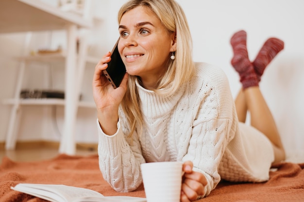 Femme tenant une tasse de thé et parler au téléphone