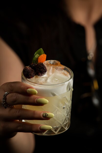 femme tenant un verre de cocktail garnie de framboises séchées