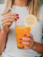 Photo gratuite femme tenant un verre de jus d'orange et de paille