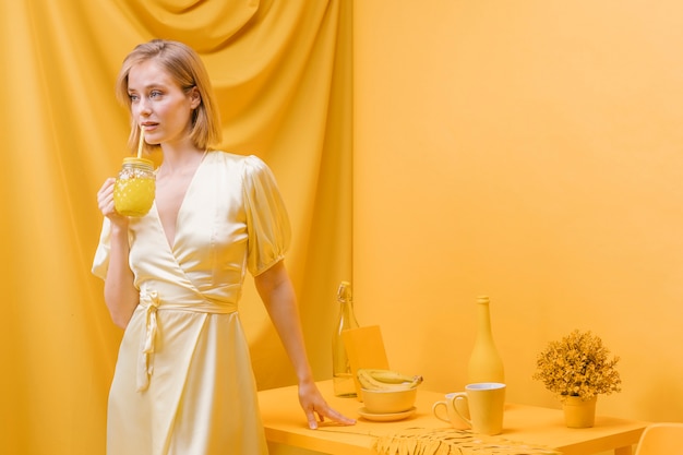 Femme tenant un verre de limonade dans une scène jaune