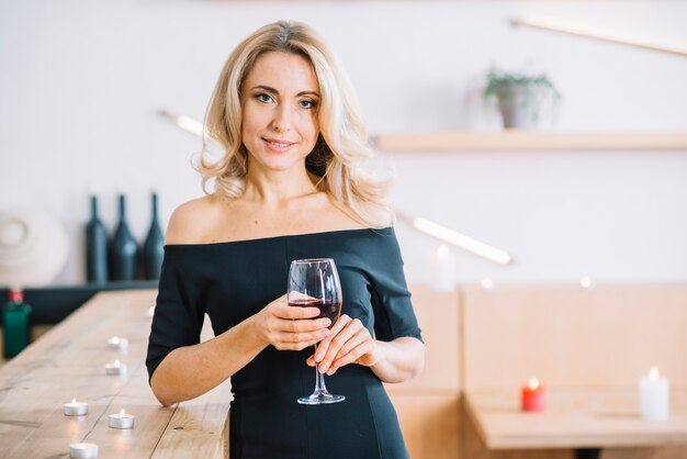 Femme tenant un verre de vin et face à la caméra