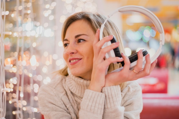 Femme, tenue, écouteurs, regarder, noël, lumières