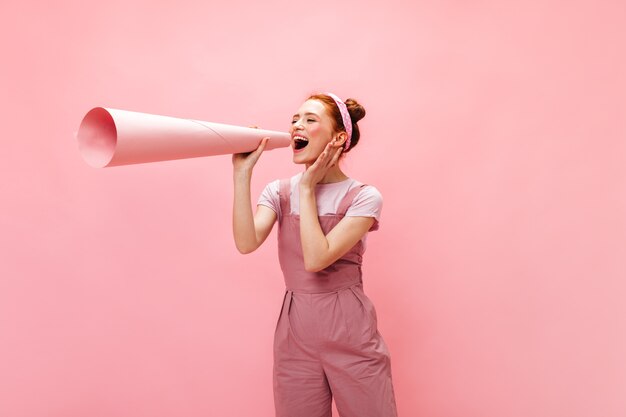 Femme en tenue rose attachée à son oreille énorme morceau de papier roulé dans un tube.