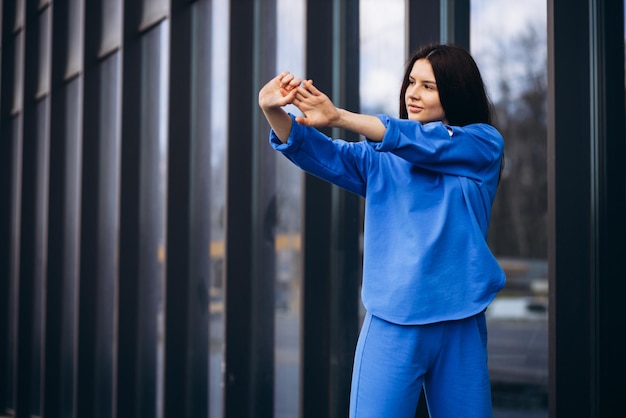 Femme en tenue de sport bleue qui s'étend à l'extérieur de la rue