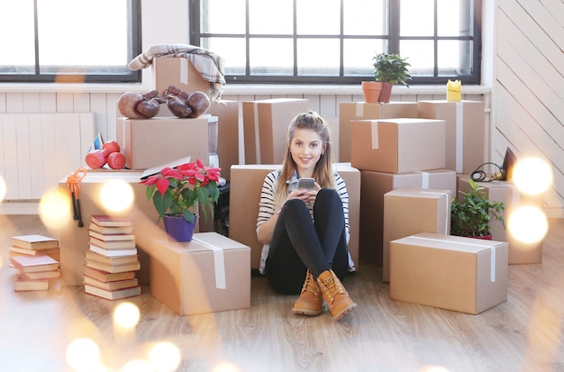 Femme a terminé avec des colis et est assise par terre en appelant un coursier