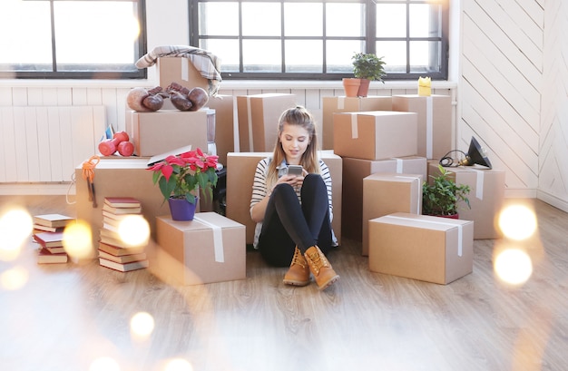 Femme a terminé avec des colis et est assise par terre en appelant un coursier