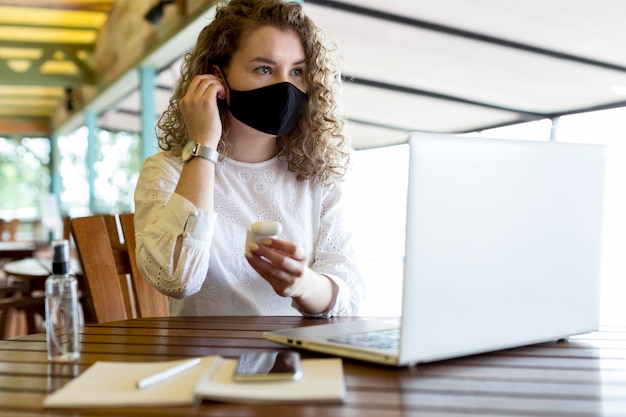 Femme à la terrasse travaillant avec masque