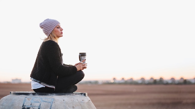 Femme avec thermos relaxant dans la nature