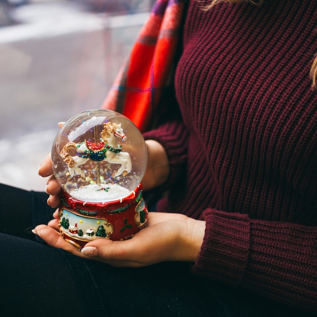 La femme tient une boule de verre avec de la neige et du cheval à l&#39;intérieur