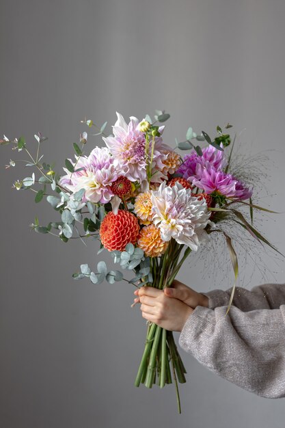 Une femme tient un bouquet festif avec des fleurs de chrysathème dans ses mains.